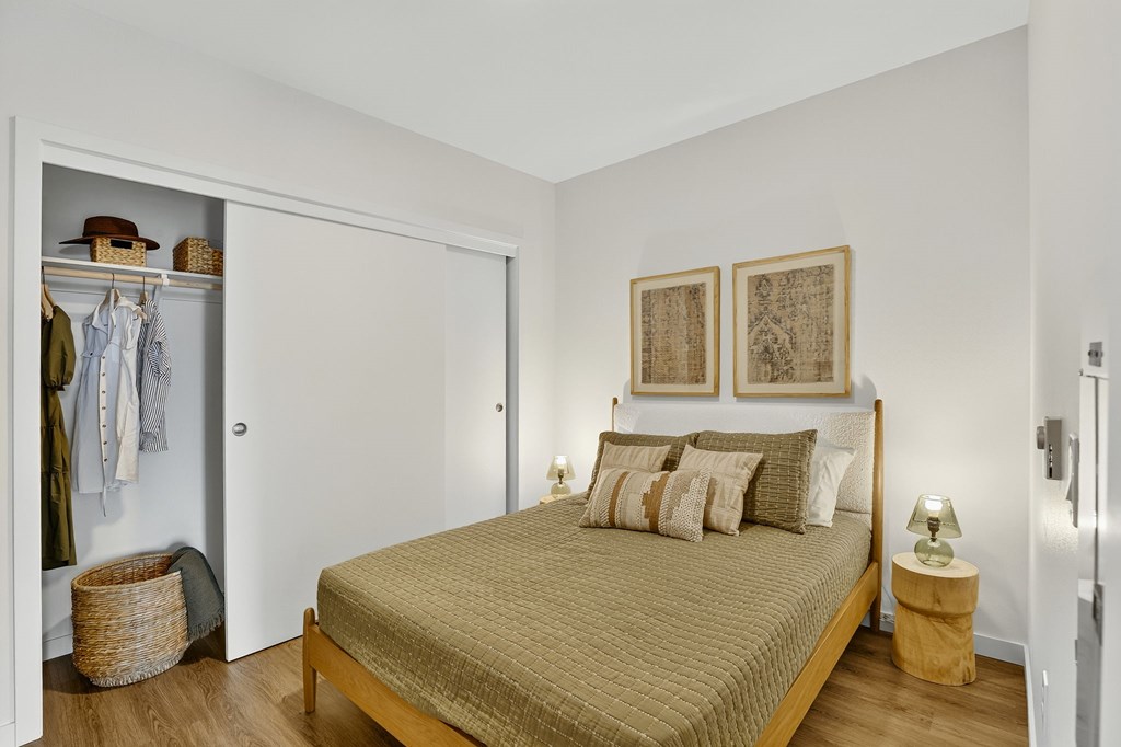 A bedroom with a bed, two pillows, a wardrobe, and a basket on the floor.