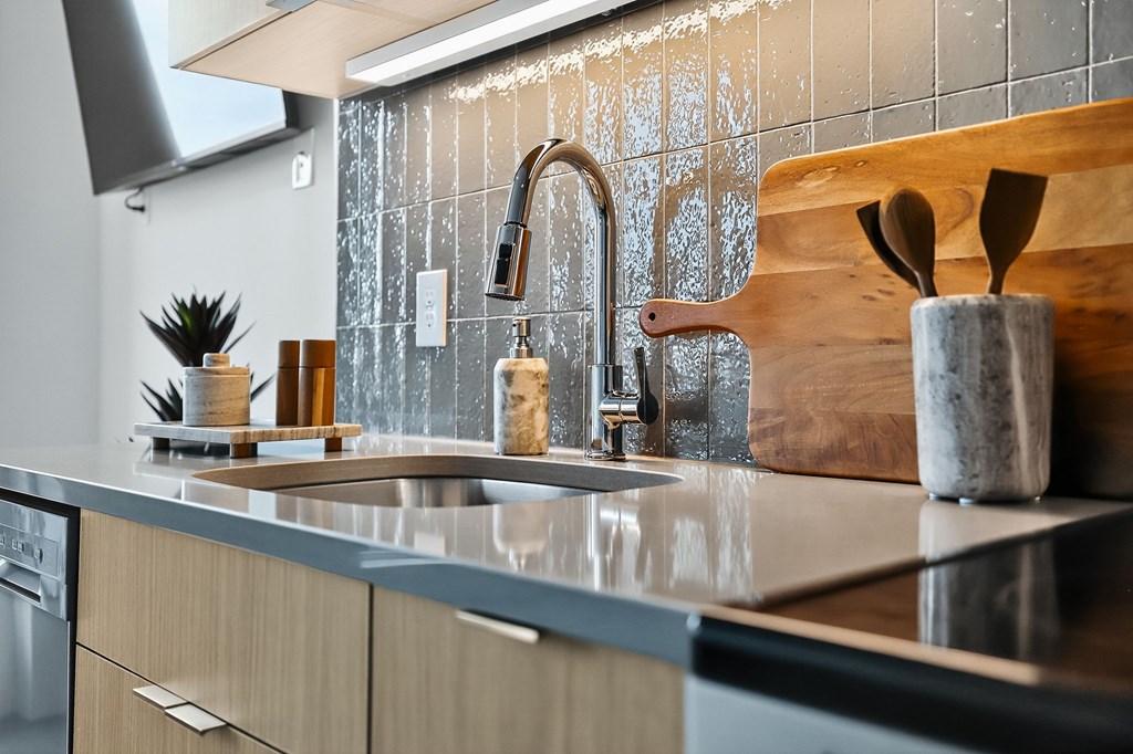 A kitchen with a wooden cutting board and a sink.