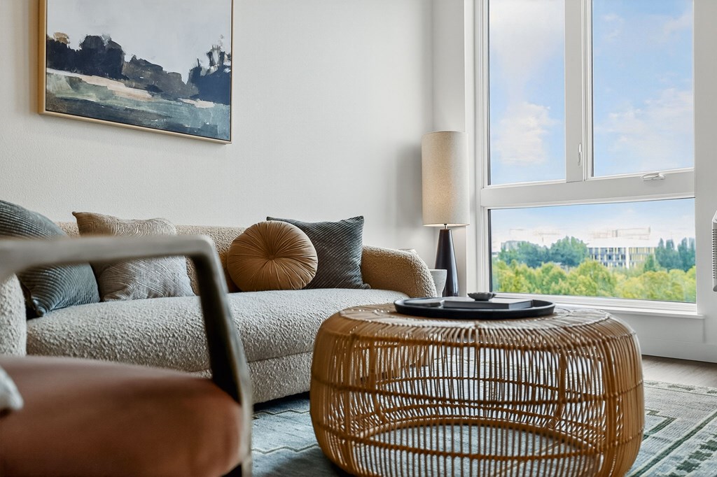 A living room with a couch, a chair, a table, and a painting on the wall.