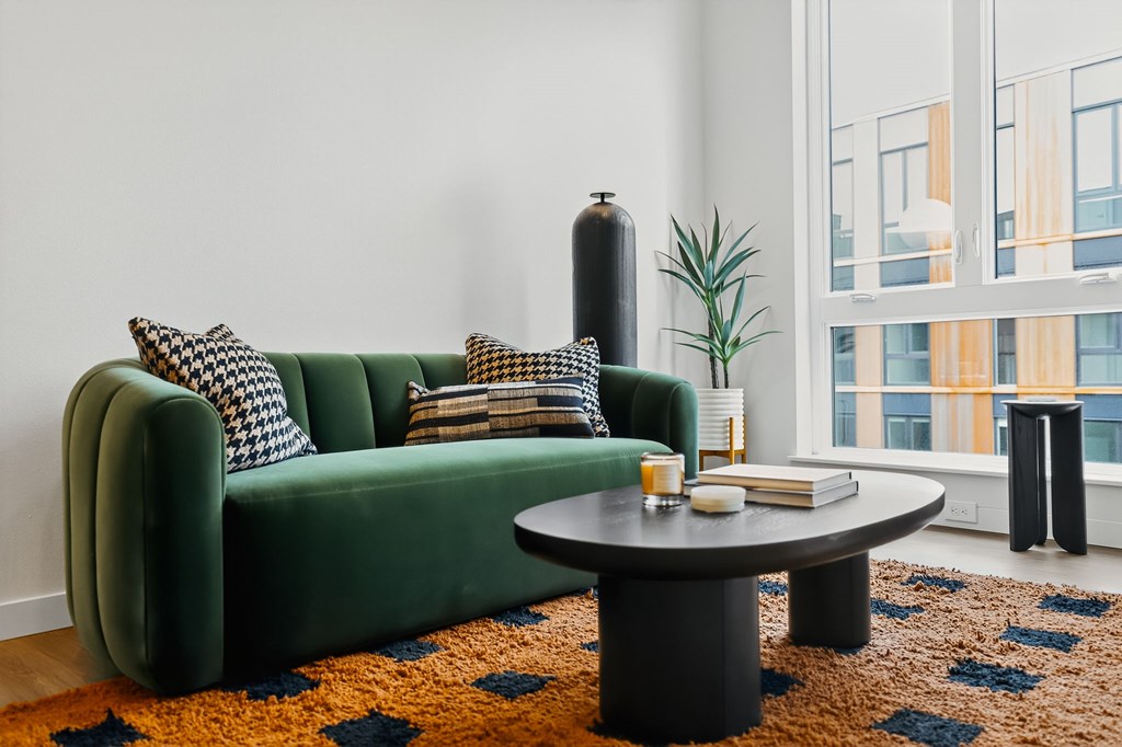 A green couch with pillows and a small table with candles on it.