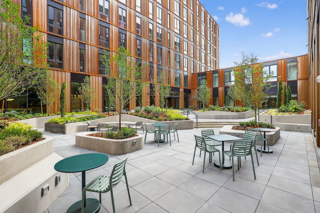 A courtyard with tables and chairs surrounded by a building.