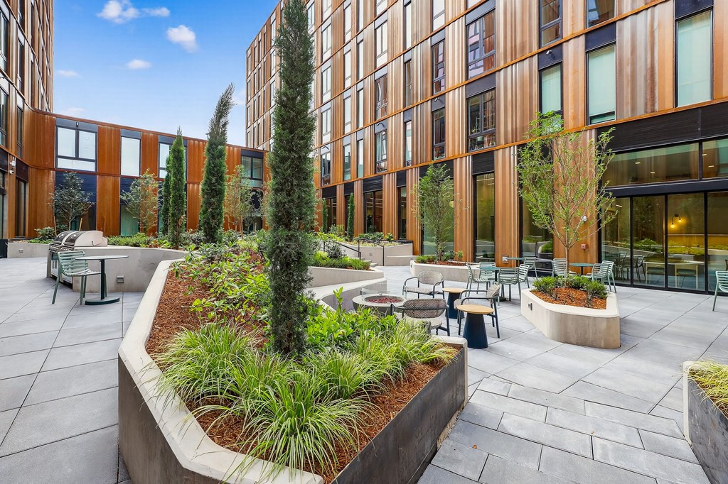 A courtyard with a planter in the middle and chairs around it.