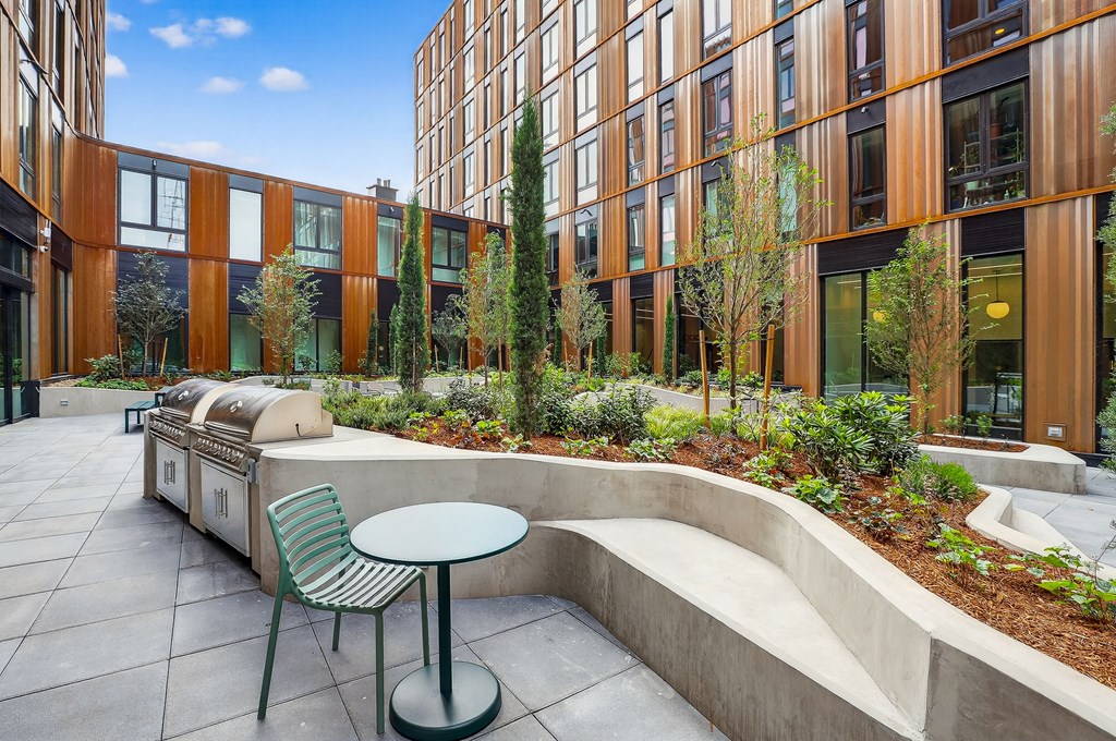 A courtyard with a table and chairs is surrounded by a building.