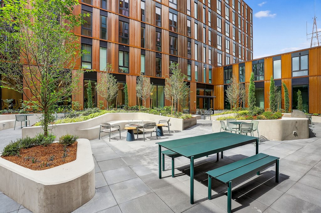 A modern building with a courtyard and a green table and benches.