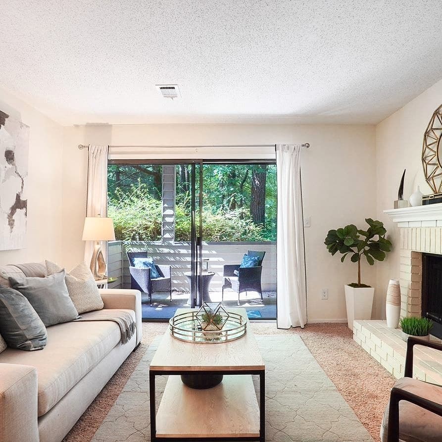 A living room with a white couch, a coffee table, and a fireplace.