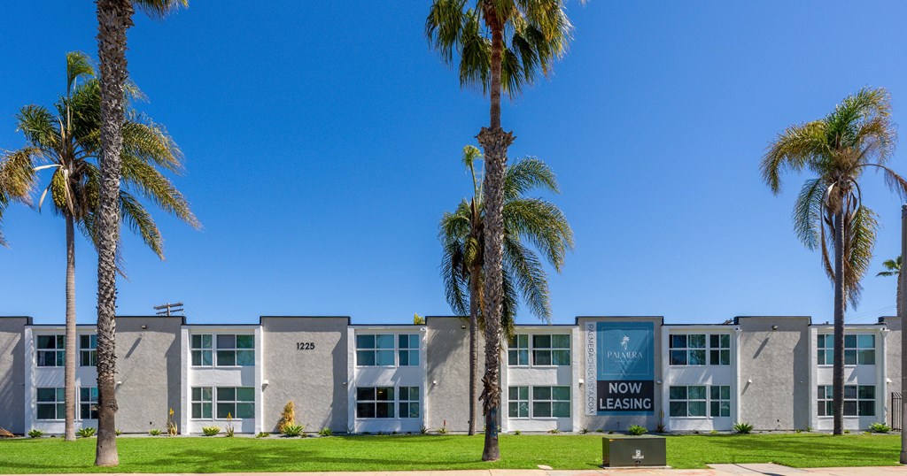 A building with a sign that says "NOW LEASING" in front of it.