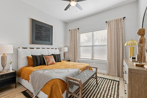 A bedroom with a bed, a chair, and a ceiling fan.