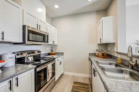 A kitchen with white cabinets and a granite countertop.