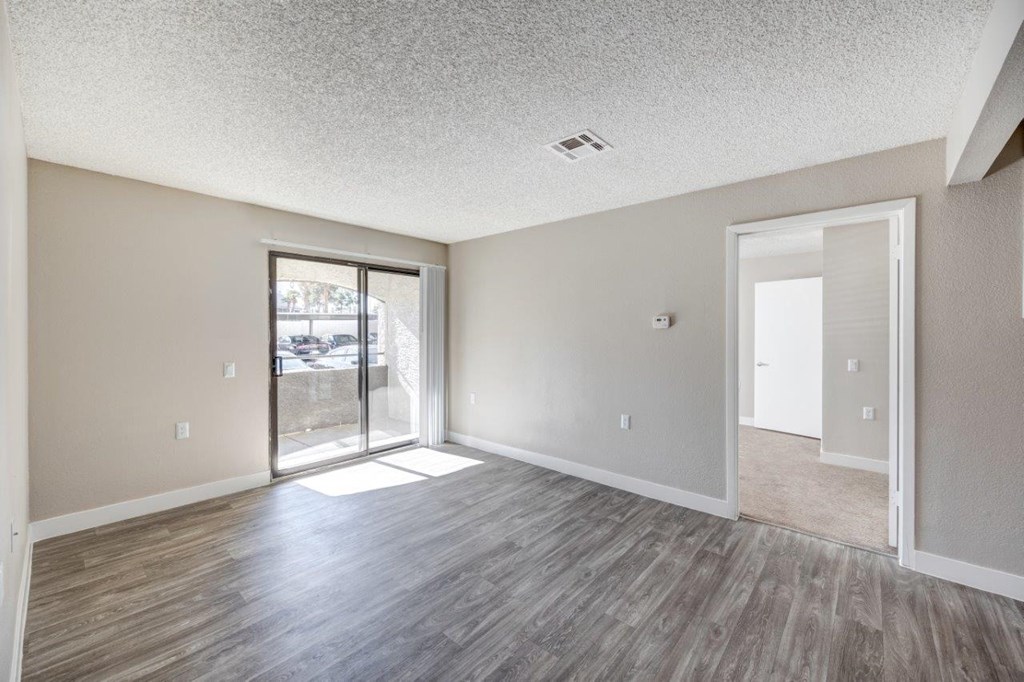 an empty living room with a sliding glass door to a patio