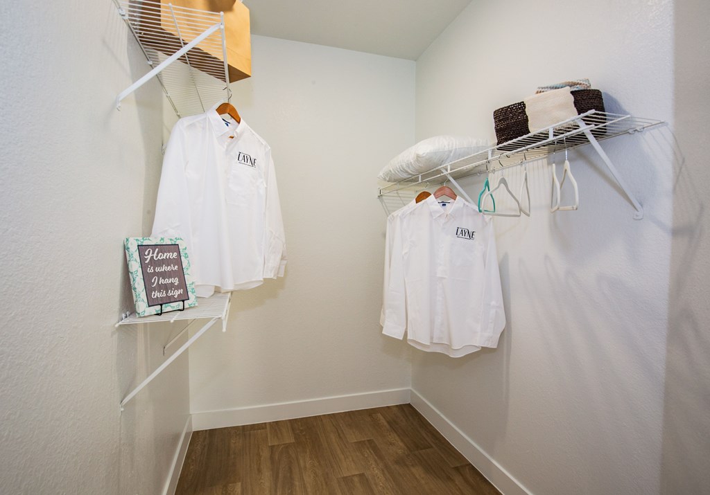 A closet with white shirts hung on a clothes rack.