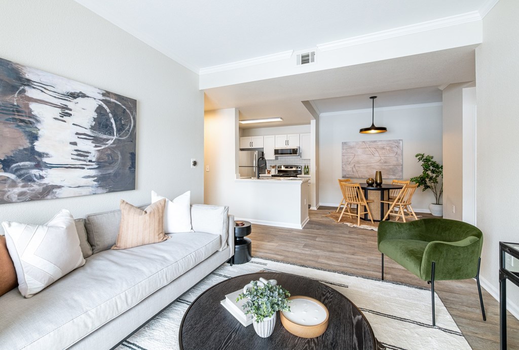A modern living room with a white sofa and a large abstract painting on the wall.