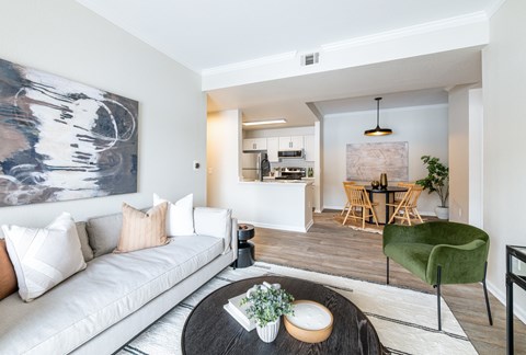 A modern living room with a white sofa and a large abstract painting on the wall.