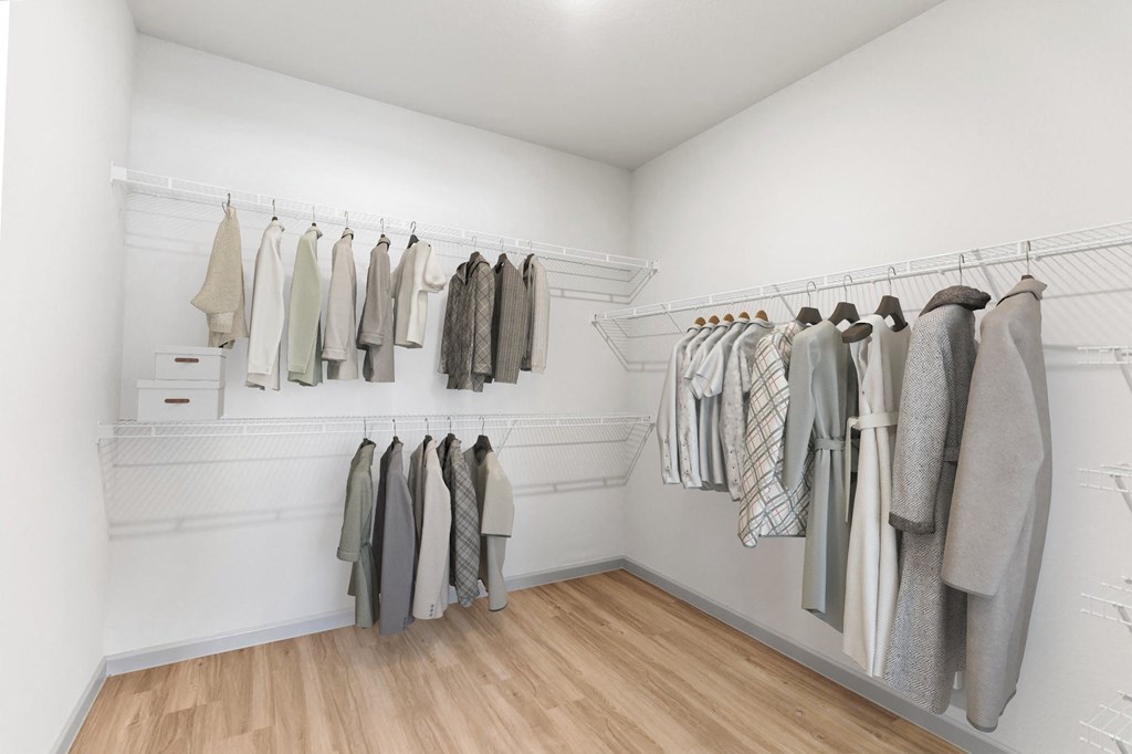 a walk in closet with white walls and wooden flooring
