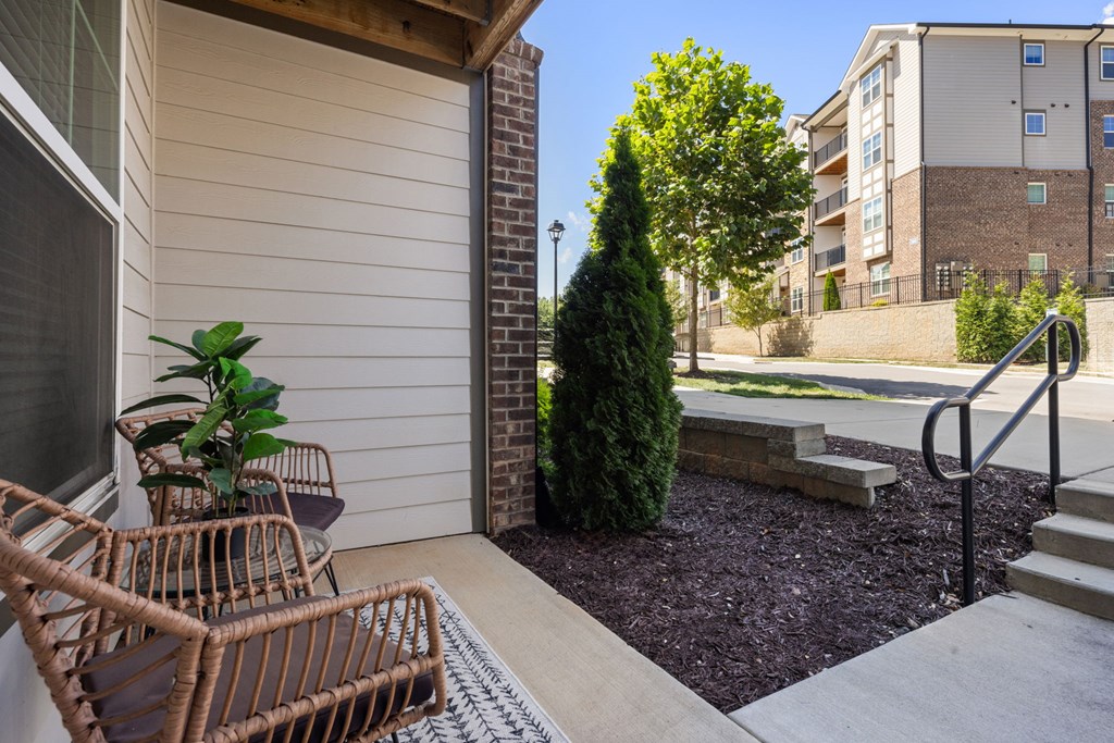 A patio with a chair and a table with a plant in it.