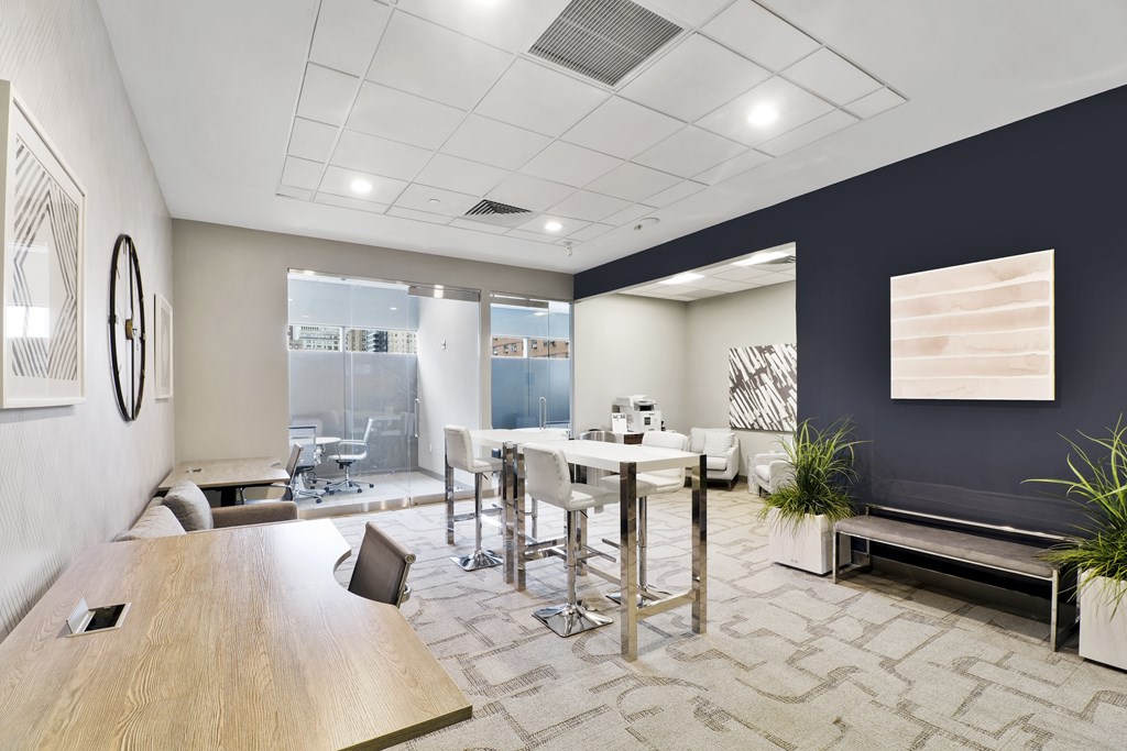 A modern office space with a long table and chairs, a bar stool, and a bench.