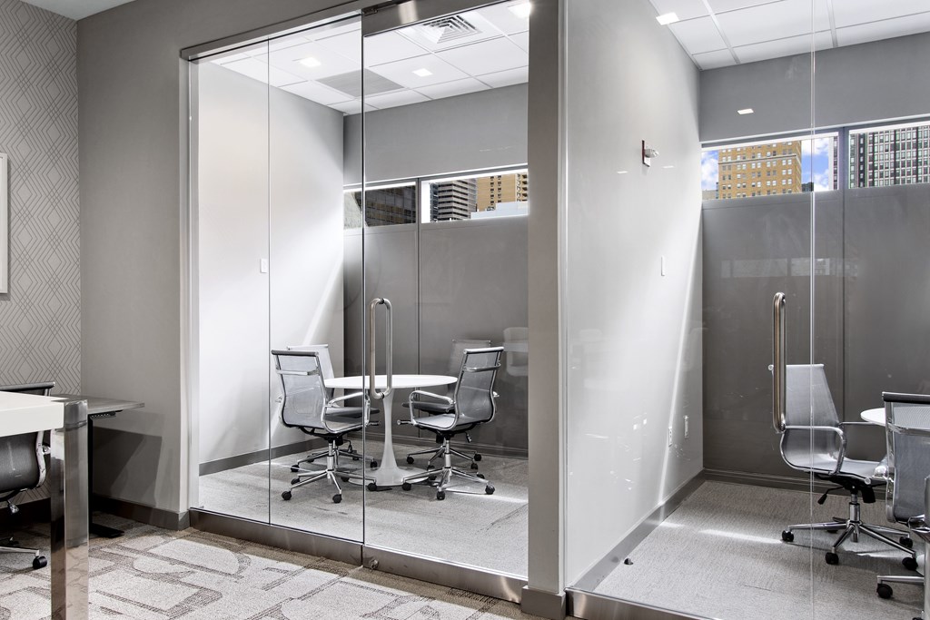 A glass wall separates an office room from a meeting room.