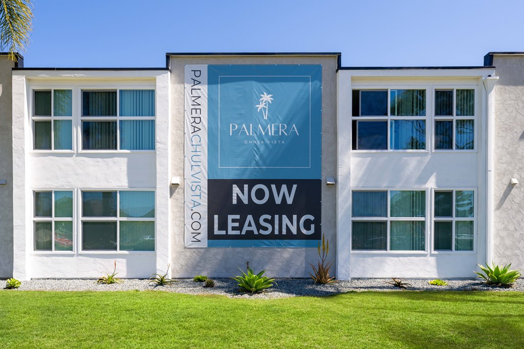 A white building with a blue sign that says Pamera now leasing.