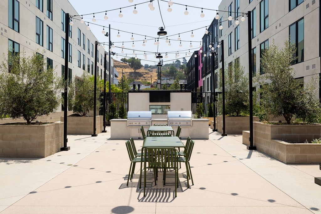 A outdoor patio with a table and chairs and grills.