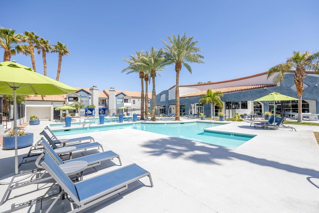 a swimming pool with lounge chairs and umbrellas