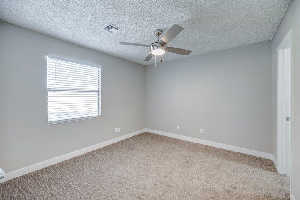 an empty room with a ceiling fan and a window