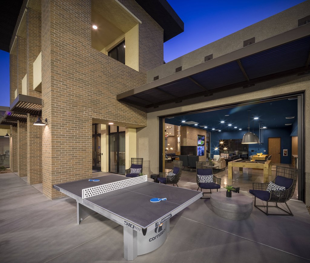 a patio with a ping pong table and chairs