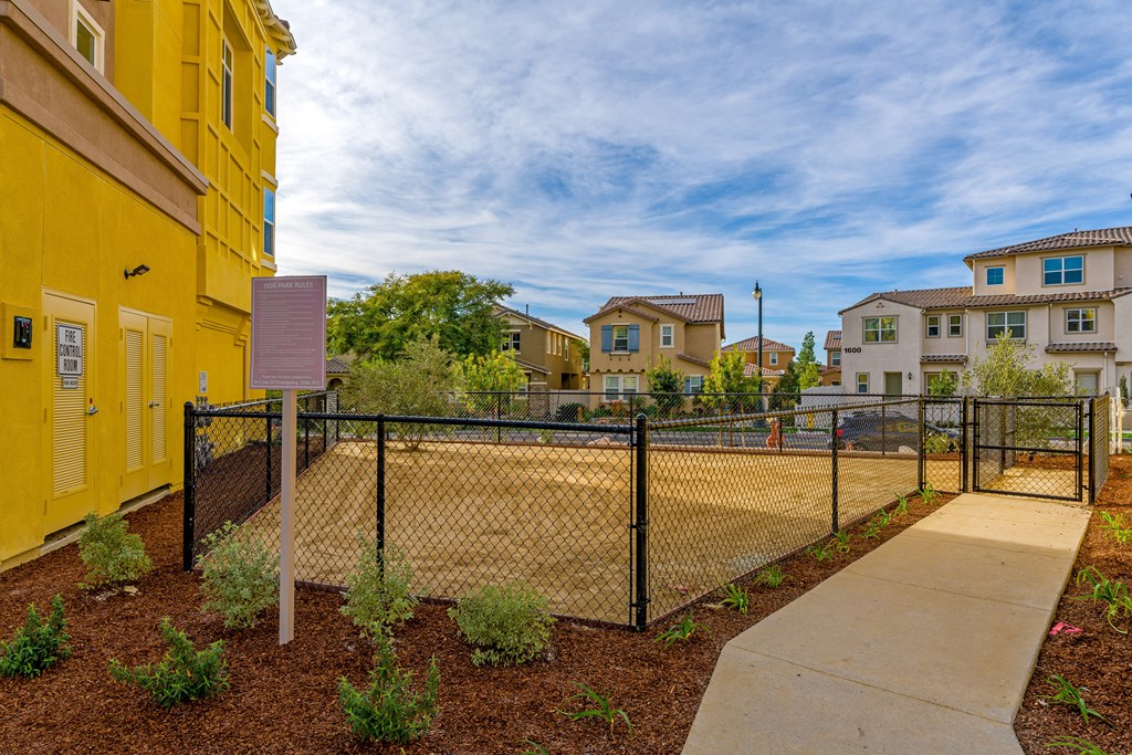 A yellow building with a black fence and a sign in front of it.
