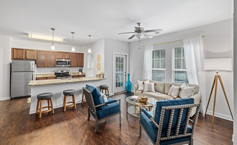 A modern kitchen and living room with a bar stool and a sofa.