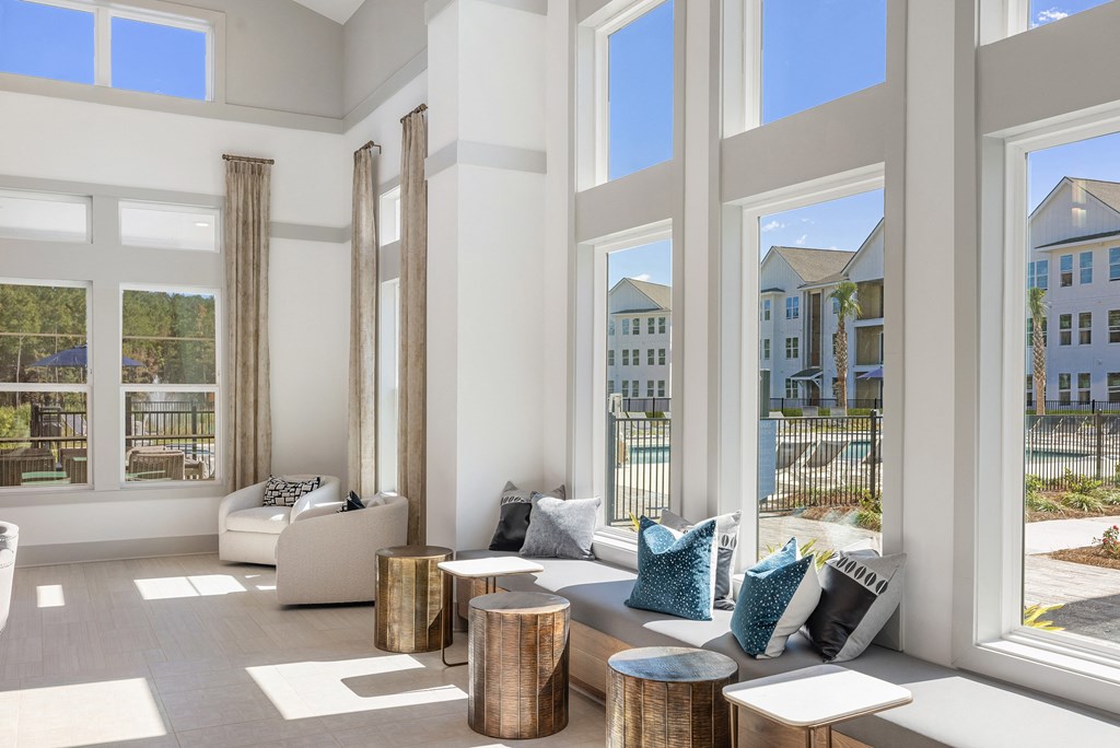 a living room with couches and tables and large windows