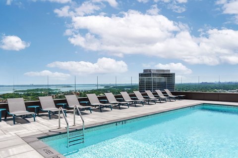 A pool with chairs and a building in the background.