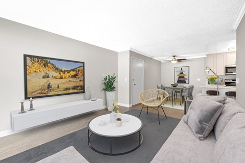 A living room with a grey couch, a white coffee table, and a painting on the wall.