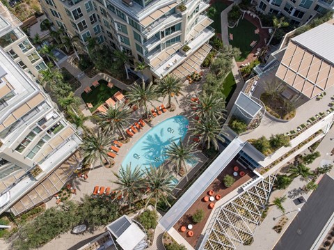 An aerial view of a pool surrounded by palm trees and orange chairs.