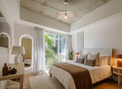 A bedroom with a large bed and a window with curtains.