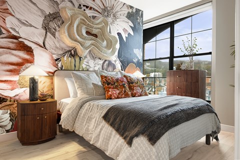 A bedroom with a large bed and a large floral mural on the wall.