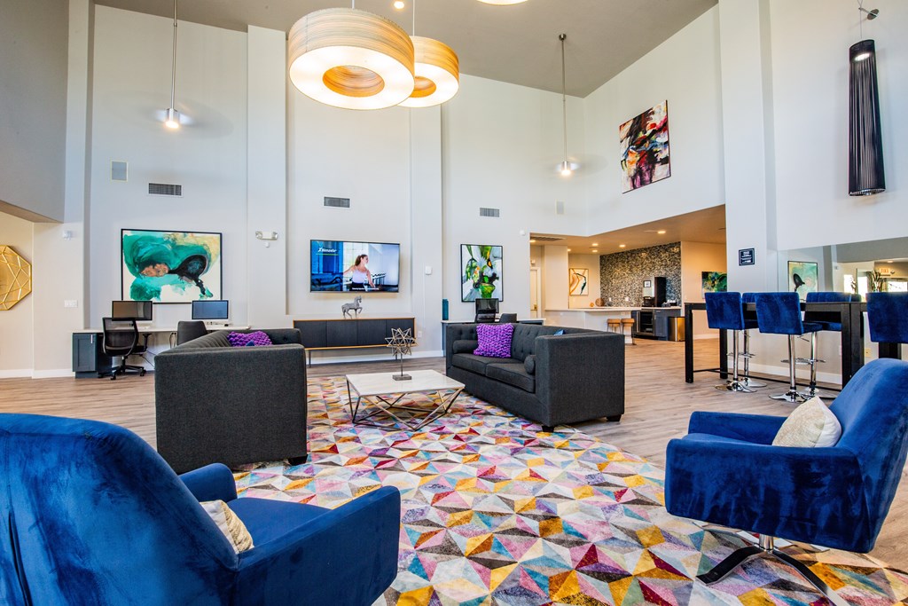 A club house seating area with blue chairs and a colorful rug.