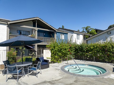 A hot tub with a table and chairs and umbrella.