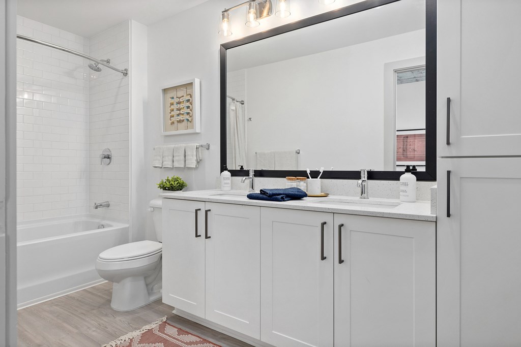 A white bathroom with a toilet, sink, and mirror.