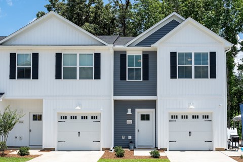 A two-story house with white and grey exterior and two garages.