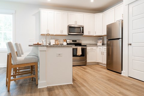 A kitchen with white cabinets and a wooden chair.