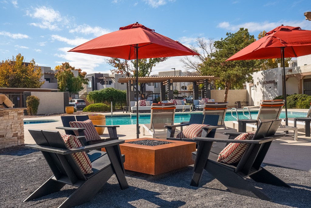 a swimming pool with chairs and umbrellas and a poolside table with chairs