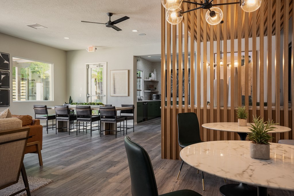 a dining room with tables and chairs and a kitchen in the background