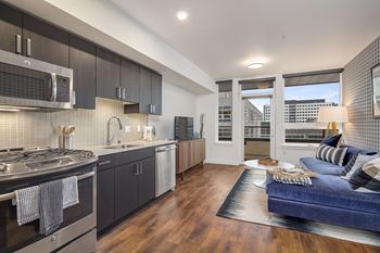 A modern kitchen with dark wood cabinets and a blue sofa in the living room.
