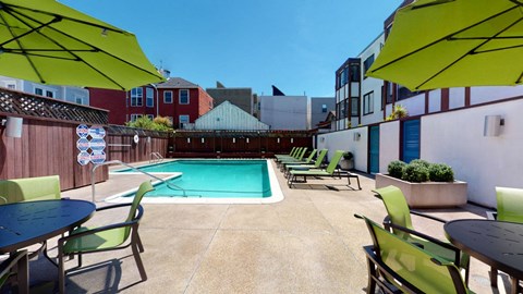 a pool with green chairs and umbrellas on a sunny day