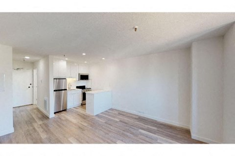 A kitchen with white cabinets and a refrigerator is visible.