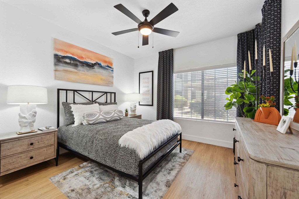 A bedroom with a bed, dresser, and ceiling fan.