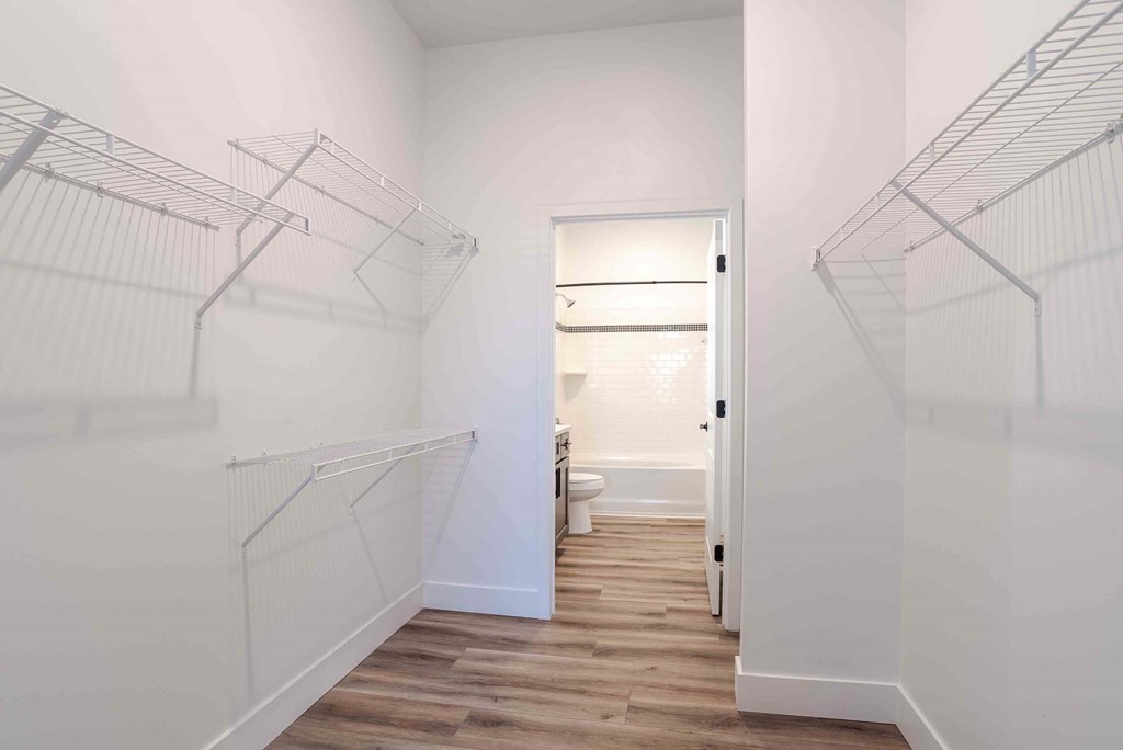 an oversized closet with white walls and wood floors