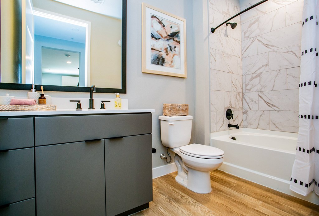 a bathroom with gray cabinets and a white bathtub