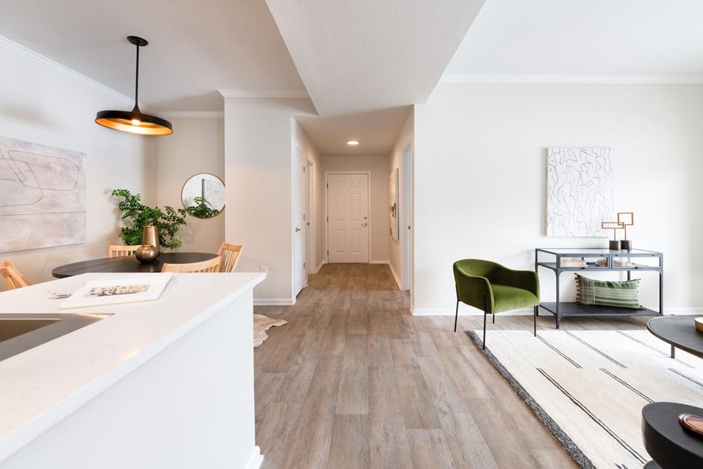 A modern kitchen with a green chair and a white counter.