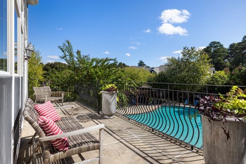 A patio with a pool and chairs.