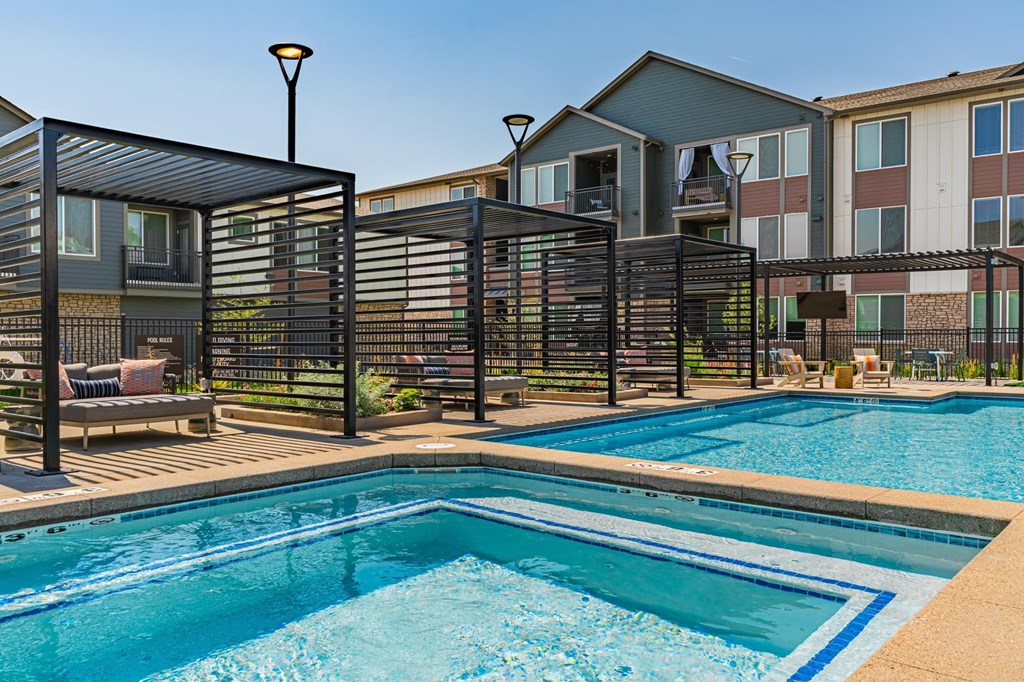 A pool surrounded by a black fence with a building in the background.