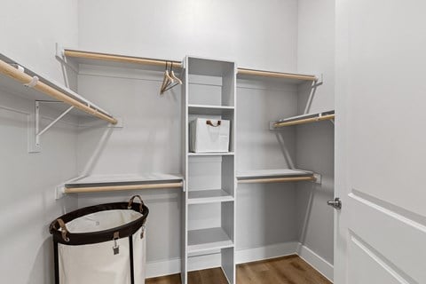 A white closet with shelves and a trash can.
